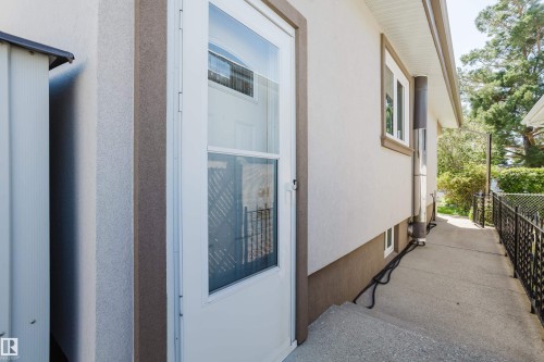 White storm door entry with glass paneling, stucco exterior, and a wrought iron style fence - 10924 35A Avenue Nw, Edmonton, AB 