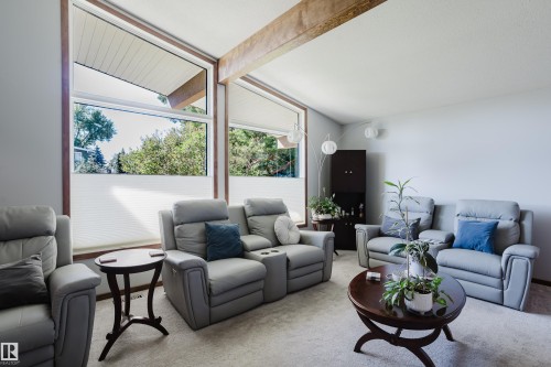 Vaulted ceiling with exposed wood beam, large picture windows, light gray wall paint, and wall-mounted spherical light fixtures - 10924 35A Avenue Nw, Edmonton, AB 