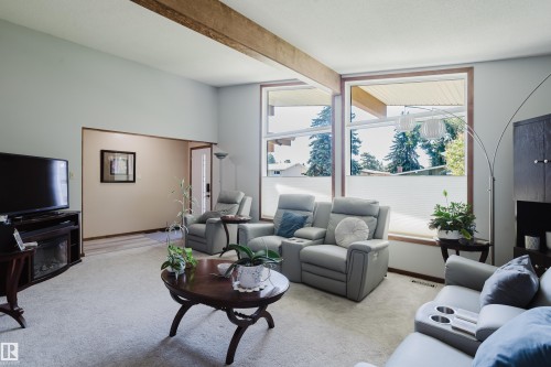 Vaulted ceiling with an exposed wood beam, large windows, and an arched entry - 10924 35A Avenue Nw, Edmonton, AB 