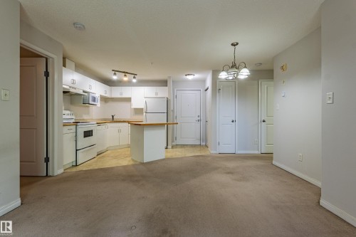 Kitchen with white cabinetry, a built-in microwave, and a breakfast bar - #316 11325 83 St Nw, Edmonton, AB 