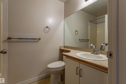 Vanity with integrated sink and chrome faucet, large wall mirror, and toilet - 