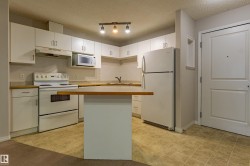 Kitchen featuring white cabinetry, light wood-finish countertops, and a full suite of white appliances - 