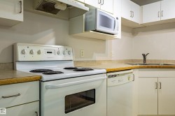 Kitchen featuring white cabinetry, an electric range, a microwave, a dishwasher, and a stainless steel sink - 