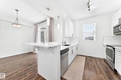 Kitchen with wood-finish flooring, white cabinetry, and stainless steel appliances - 
