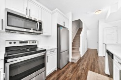 Kitchen featuring stainless steel appliances, white cabinetry, a subway tile backsplash, and light countertops - 