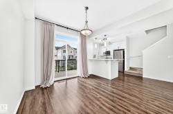 Spacious open-concept layout with wood-finish flooring, white cabinetry, stainless steel appliances, and a private balcony - 