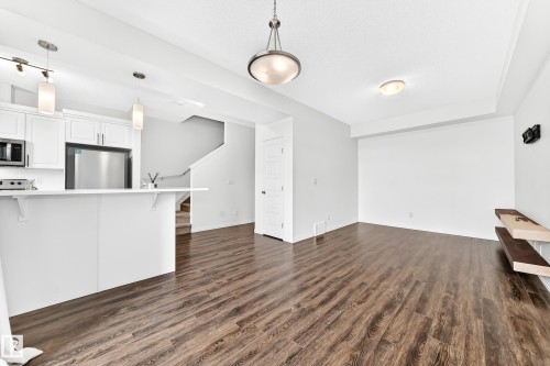 Wood-finish flooring throughout, white cabinetry, stainless steel appliances, and integrated shelving - 20008 19 Avenue Nw, Edmonton, AB 
