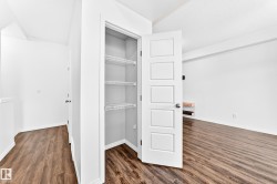 Wood-finish flooring throughout, white interior doors, and a built-in closet with wire shelving - 