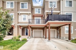 Multi-level residence featuring horizontal siding, multiple windows, a ground-level covered entry, an upper-level balcony with a black railing, and a two-car garage - 
