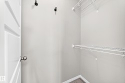 White wire shelving, dark gray carpet, matte black wall hooks, and a paneled interior door with a brushed nickel knob - 