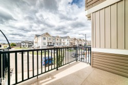 Balcony with black metal railings, textured concrete flooring, and horizontal siding - 