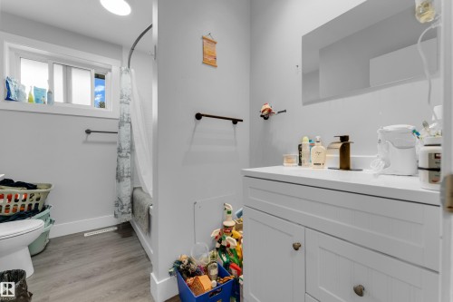 White vanity with a single basin sink, bronze-finish faucet, and a large wall-mounted mirror - 14216 58 Street Nw, Edmonton, AB 