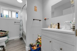 White vanity with a single basin sink, bronze-finish faucet, and a large wall-mounted mirror - 