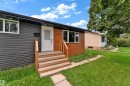 Contemporary exterior with horizontal siding, wood-finish accent paneling, and a white entry door - 14216 58 Street Nw, Edmonton, AB 