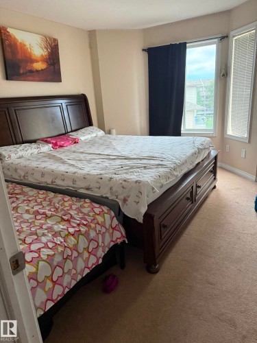 Carpeted room with a bay window featuring blinds and a dark curtain rod - #9 2505 42 St Nw, Edmonton, AB 