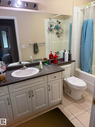 White vanity with panel-front cabinetry, dark-finish countertop, and integrated sink - #9 2505 42 St Nw, Edmonton, AB 