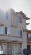 Multi-level facade with light-toned horizontal siding, multiple bay windows, and a prominent front door with an arched transom window - 