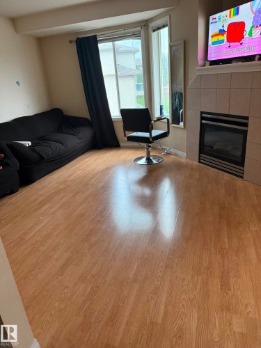 Wood-finish flooring, bay window, tile-surround fireplace, and a mantel - #9 2505 42 St Nw, Edmonton, AB 