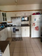 Kitchen featuring white cabinetry with wood trim, ceramic tile flooring, and a tile backsplash - 