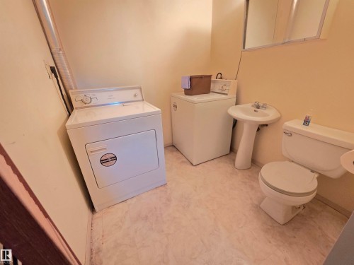Laundry area with a freestanding washer and dryer, pedestal sink, and toilet - 10438 147 Street Nw, Edmonton, AB 