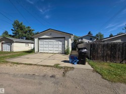 Detached garage with a paneled door, concrete driveway, and stucco exterior - 