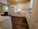 Kitchen featuring wood-finish flooring, white cabinetry, white appliances, and a white countertop - 10438 147 Street Nw, Edmonton, AB 