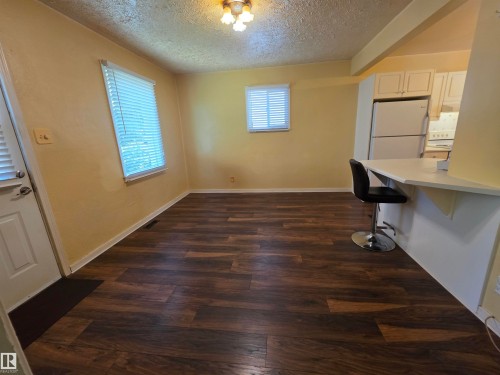 Wood-finish flooring throughout, multiple windows with blinds, and a breakfast bar - 10438 147 Street Nw, Edmonton, AB 