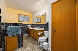 Bathroom featuring a wood-finish vanity with an integrated sink, a wall-mounted mirror, and tile flooring - 