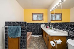 Bathroom featuring a built-in vanity with an integrated sink, a rectangular mirror with sconce lighting, and a bathtub - 