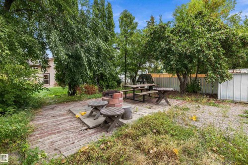 Brick fire pit, concrete patio, wood fence, mature trees, and a storage shed - 10621 60A Avenue Nw, Edmonton, AB 