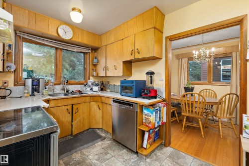 Kitchen featuring wood cabinetry, stainless steel dishwasher, and a double window above the sink - 10621 60A Avenue Nw, Edmonton, AB 