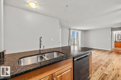 Kitchen island with dark countertop, double stainless steel sink, and gooseneck faucet - #110 4309 33 St, Stony Plain, AB 