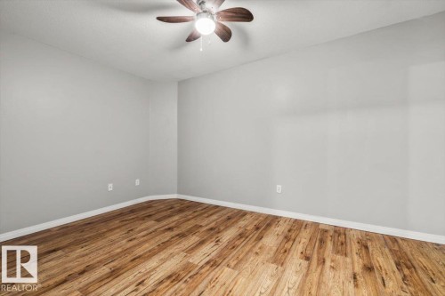 Light gray wall paint, wood-finish flooring, white trim, and a ceiling fan with integrated lighting - #110 4309 33 St, Stony Plain, AB 