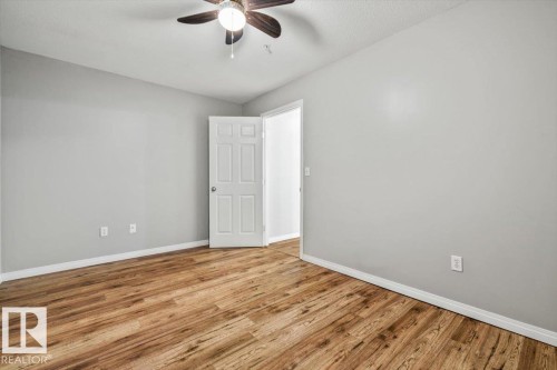 Wood-finish flooring, light gray walls, white trim, and a ceiling fan - #110 4309 33 St, Stony Plain, AB 