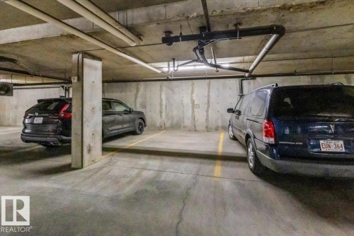 Concrete parking area with marked spaces and overhead piping - #110 4309 33 St, Stony Plain, AB 
