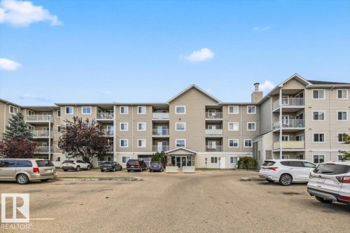 Multi-story residential building featuring balconies, multiple windows, a central entrance, and an external chimney - #110 4309 33 St, Stony Plain, AB 