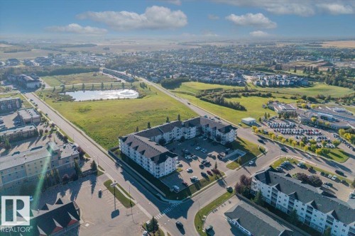 Expansive neighborhood with commercial properties, residential buildings, and a visible pond - #110 4309 33 St, Stony Plain, AB 