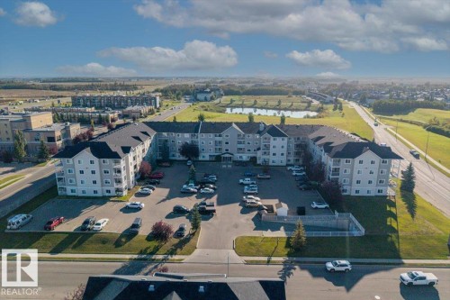 Multi-story residential building with light-toned siding and dark shingle roofing - #110 4309 33 St, Stony Plain, AB 
