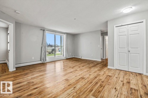 Wood-finish flooring throughout, sliding glass door, white bi-fold closet doors, and recessed ceiling lighting - #110 4309 33 St, Stony Plain, AB 