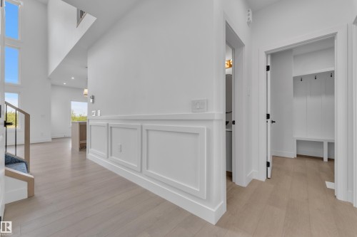 Entryway featuring wood-finish flooring, wainscoting, a built-in bench with coat hooks, and a contemporary staircase with iron balusters - 1129 Starling Drive Nw, Edmonton, AB 