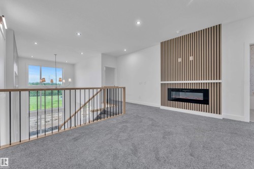 Loft area featuring an electric fireplace with a slatted accent wall, recessed lighting, and a wood and metal railing - 1129 Starling Drive Nw, Edmonton, AB 