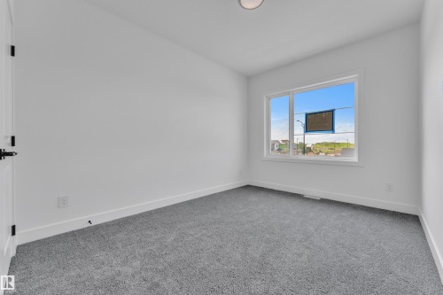Room with grey carpet flooring, white walls, and a large window - 1129 Starling Drive Nw, Edmonton, AB 