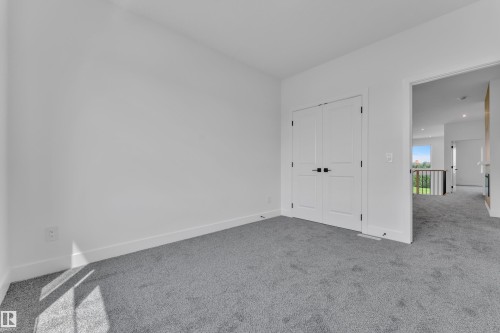 White walls with carpet flooring, double panel doors with black hardware, and a wide entryway - 1129 Starling Drive Nw, Edmonton, AB 