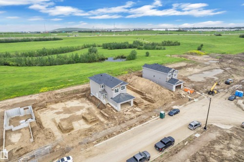 New construction home with a two-story design, attached garage, and light gray siding - 1129 Starling Drive Nw, Edmonton, AB 