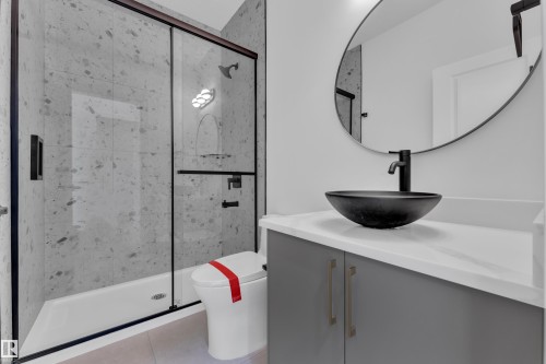 Spacious shower with stone-finish tile surround and black-framed glass enclosure - 1129 Starling Drive Nw, Edmonton, AB 