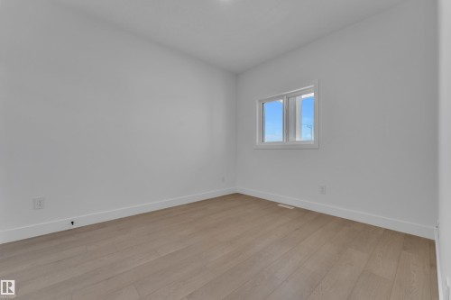 Light wood-finish flooring and white walls with a prominent window - 1129 Starling Drive Nw, Edmonton, AB 