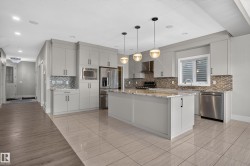 Kitchen featuring light gray cabinetry, stainless steel appliances, a center island with a light-toned countertop, and mosaic tile backsplash - 