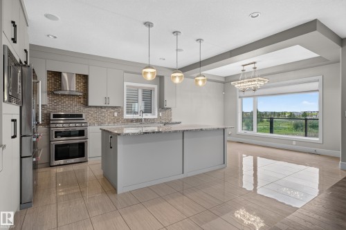 Gourmet kitchen with stainless steel appliances, granite island, and mosaic tile backsplash - 2219 22 Street Nw, Edmonton, AB 