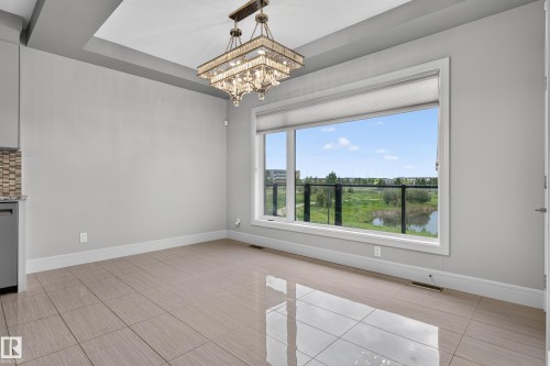 Tray ceiling with a crystal chandelier, large window with a roller shade, and glass railing - 2219 22 Street Nw, Edmonton, AB 