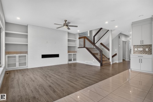 Built-in shelving, integrated fireplace, wood-finish flooring, glass panel staircase, and recessed lighting - 2219 22 Street Nw, Edmonton, AB 